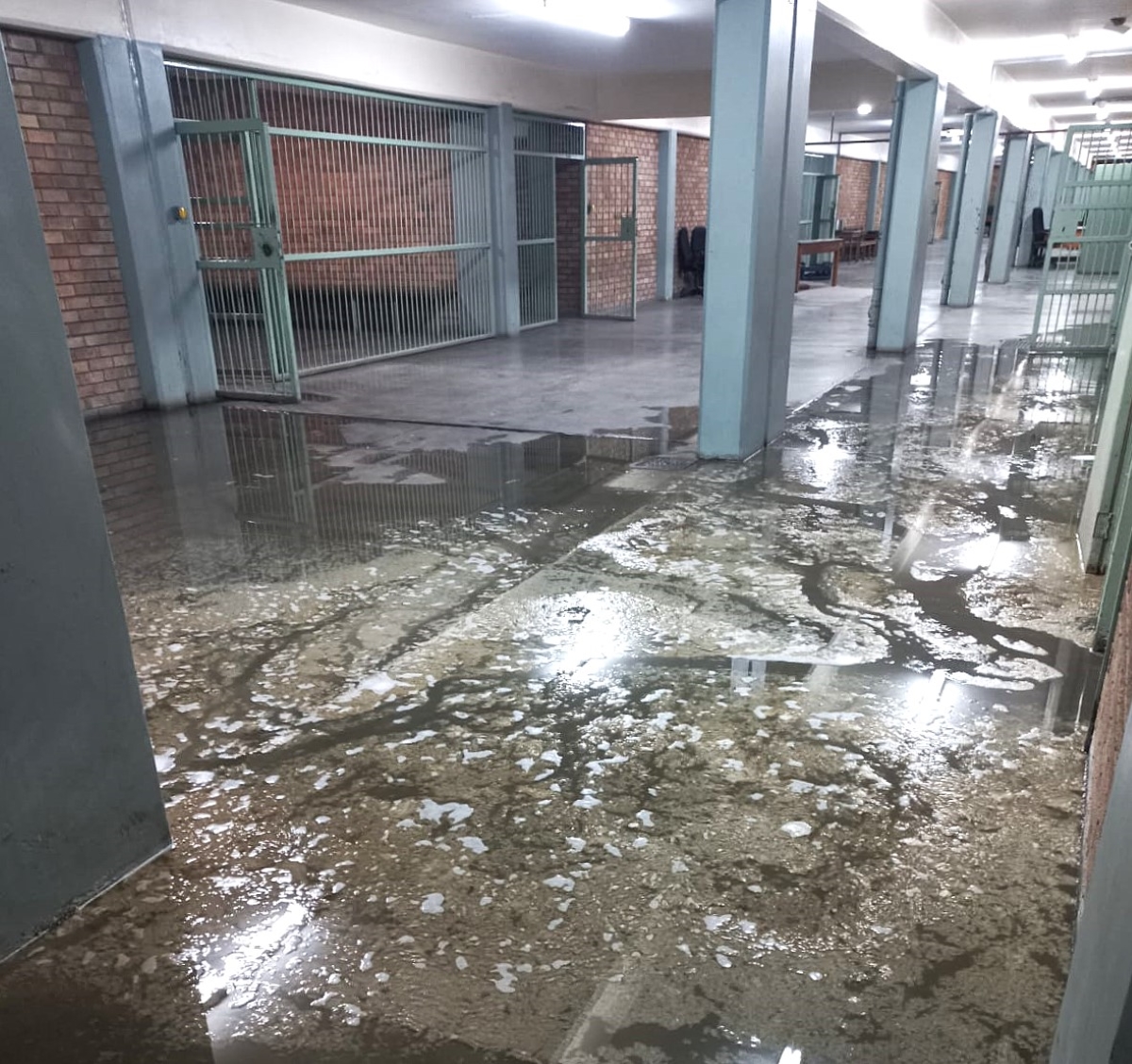 Die loopvlak tussen die polisie se kantore en badkamers op pad na die aanhoudingselle enkeldiep in rioolvuil.