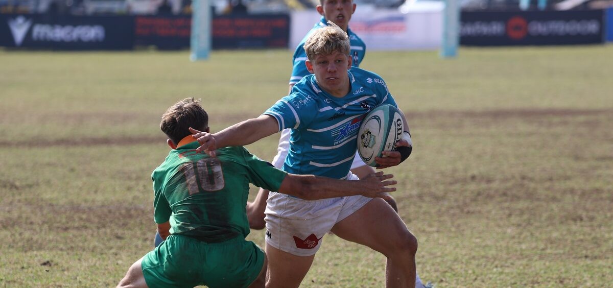 Hoërskool Garsfontein se Keagan Knighton probeer verby die Hoërskool Rustenburg se losskakel, Ricardo Enos, glip.