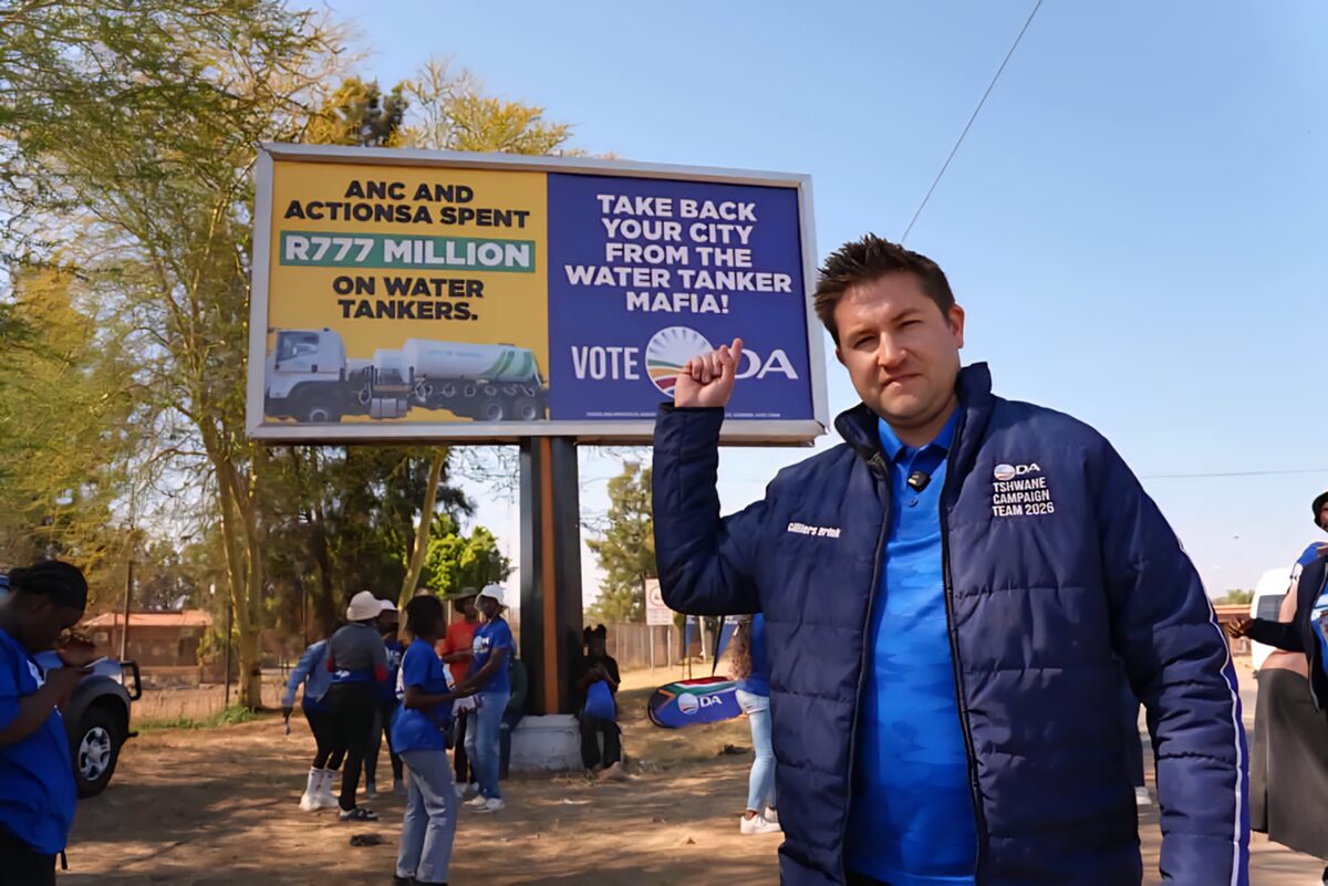Cilliers Brink by die DA se reklamebord in Hammanskraal.